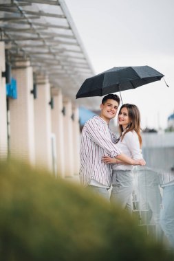 Genç güzel çift birbirleri ile bakarak şemsiyenin altına yağmurlu günde sokakta seviyorum. Sevgi ve çift ilişkiler kavramı.