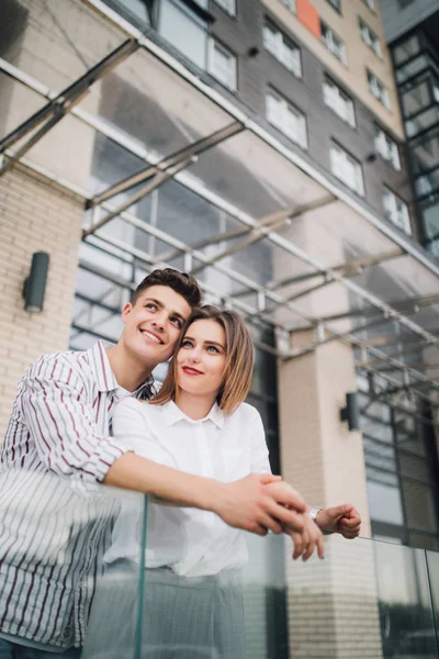 Unga förälskade par stående på terrassen på deras nya moderna byggnad utomhus — Stockfoto