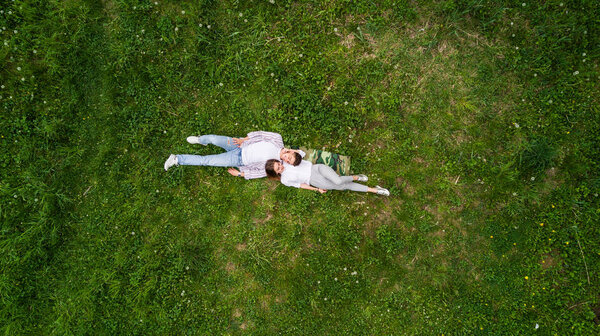 Carefree couple lying on grass together in love frome above