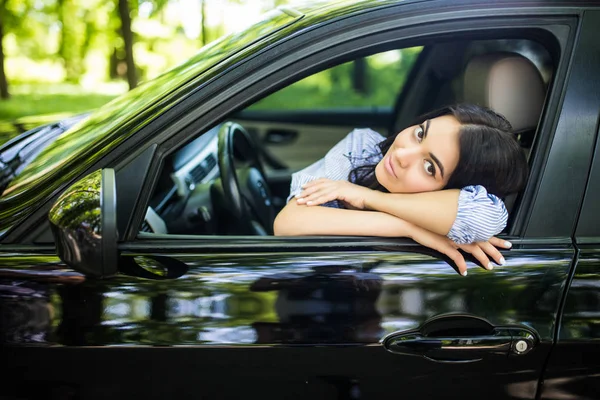 Vue latérale d'une femme souriante assise à l'intérieur d'une voiture et regardant par la fenêtre — Photo