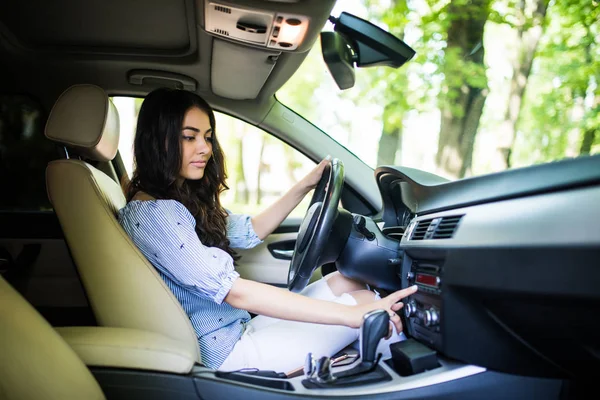 Op zoek naar favoriete muziek. Jonge aantrekkelijke vrouw glimlachend en op knoppen te drukken tijdens het auto rijden — Stockfoto