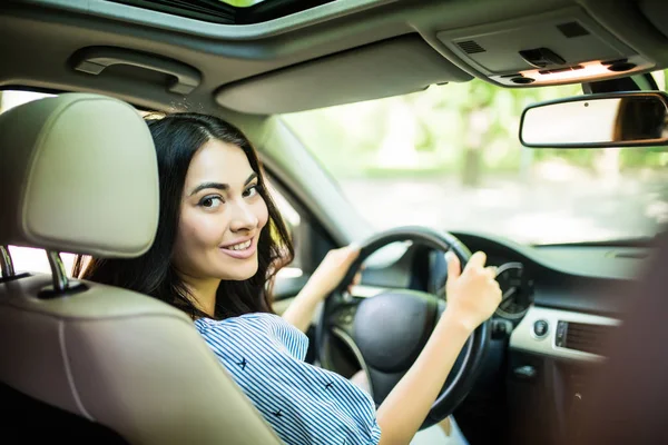Femme conductrice regardant par-dessus le dos du siège conducteur à l'arrière de la voiture brisant sa concentration sur la route — Photo