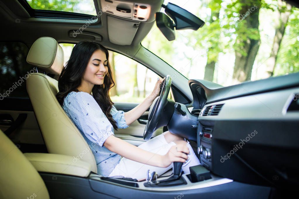 Young woman changing gears in car. Driving a car.