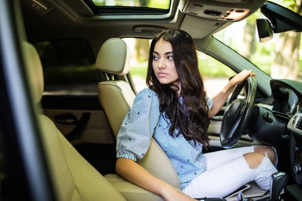 Joven mujer de belleza en el interior del coche mantiene la rueda girando y conducir de vuelta — Foto de Stock