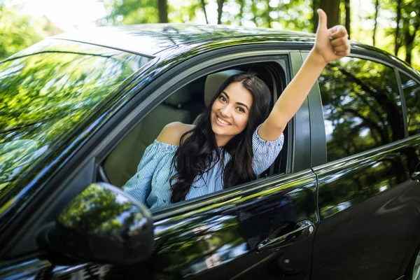 Happy tersenyum wanita di dalam mobil tampak melemparkan jendela dan menunjukkan ibu jari ke atas — Stok Foto