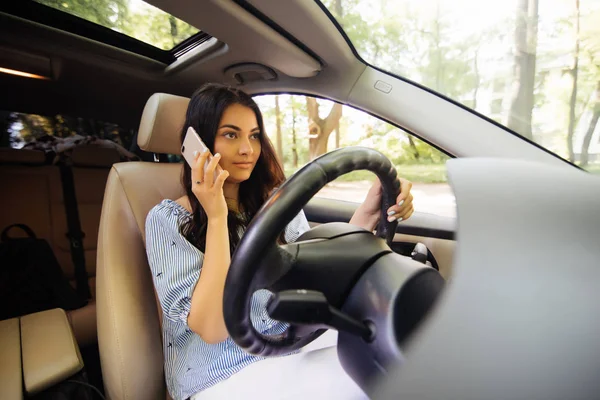 Молодая женщина в машине. Молодая женщина красивая брюнетка говорит по мобильному телефону — стоковое фото