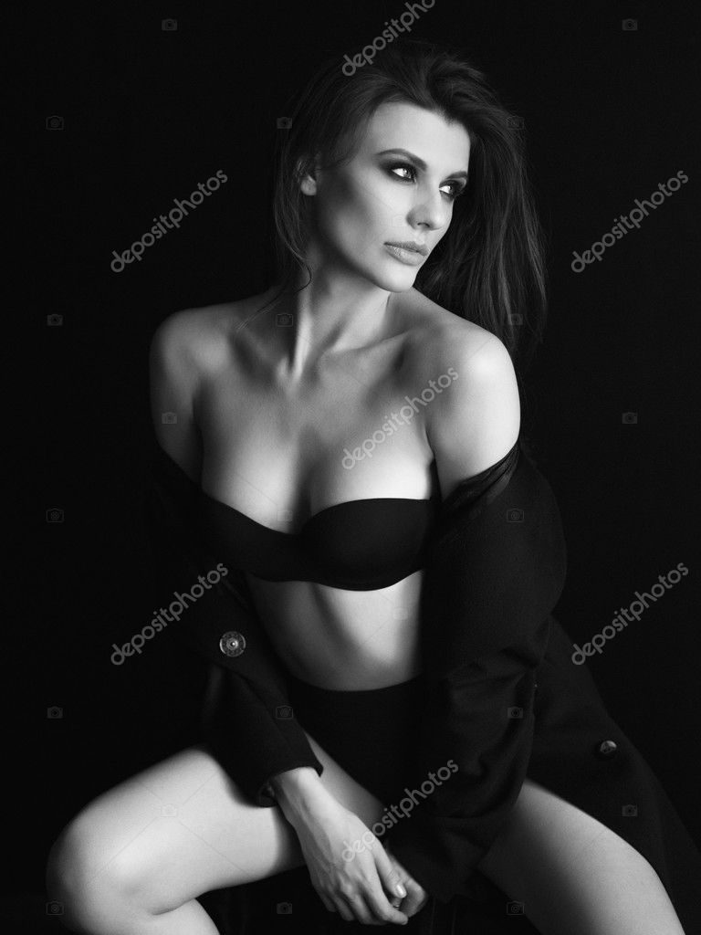 beautiful girl in glasses and black bra sitting on a bed фотография Stock