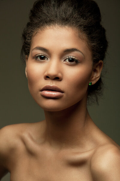 Fashionable portrait of an extraordinary beautiful naked african american female model with perfect smooth glowing mulatto skin and full lips, studio shoot