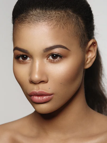 Portrait à la mode d'un magnifique modèle afro-américain extraordinaire avec une peau lisse et éclatante, des lèvres pleines et une coupe de cheveux rasée, un tournage en studio, un fond clair — Photo