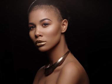 Portre ile mükemmel pürüzsüz parlak melez deri güzel çıplak bir Afrikalı-Amerikalı kadın moda, tam altın dudaklar, traş saç kesimi ve altın kolye, stüdyo çekimi, yapmak