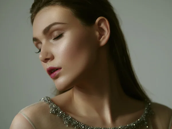 Retrato de uma jovem mulher bonita vestida inteligente no fundo cinza no elegante vestido de noite bege com olhos fechados e maquiagem expressiva — Fotografia de Stock