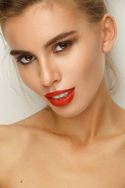 Seksi güzel genç bir kadın ile mükemmel makyaj (pürüzsüz parlak deri, geniş bakımlı kaşları, kırmızı ruj, parlak manikür ve dumanlı gözler), stüdyo çekimi, açık renkli Glamour portresi
