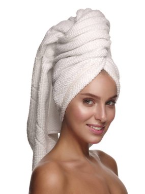 Portrait of a young pretty and charming smiling girl with a towel on her head, who is doing daily skin care procedures after the shower, white isolated studio background clipart