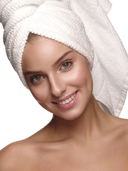 Portrait of a young girl with pure, healthy, smooth and natural glowing skin without any makeup, who is doing daily skincare after the shower with the towel on her head, white isolated background — Stockfoto