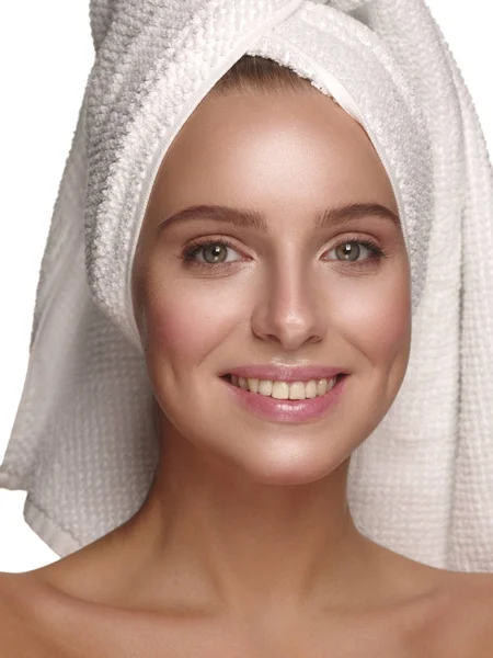 Portrait of a young girl with pure, healthy, smooth and natural glowing skin without any makeup, who is doing daily skincare after the shower with the towel on her head, white isolated background — Stockfoto