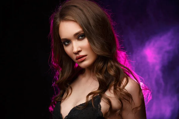 Studio portrait of a young confident and beautiful woman with long wavy hair and expressive makeup on the black background, backlight — Stock Photo, Image