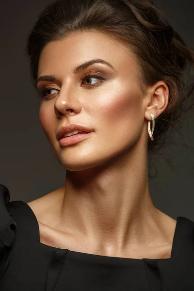 Retrato de una hermosa, autosuficiente y confiada joven con el pelo recogido en el elegante vestido negro con maquillaje, fondo oscuro, foto de estudio — Foto de Stock