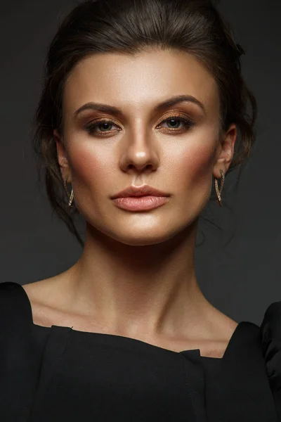 Ritratto di una giovane donna bella, autosufficiente e sicura di sé con i capelli raccolti nell'elegante abito nero con trucco, sfondo scuro, foto di studio — Foto Stock