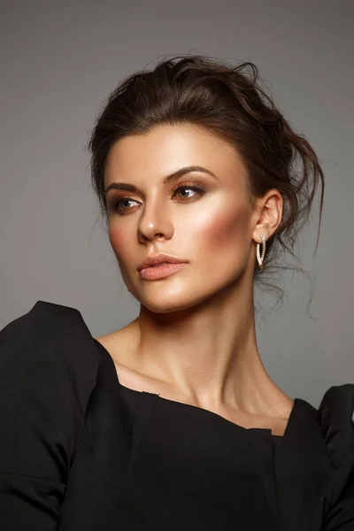 Retrato de una hermosa, autosuficiente y confiada joven con el pelo recogido en el elegante vestido negro con maquillaje, fondo oscuro, foto de estudio — Foto de Stock