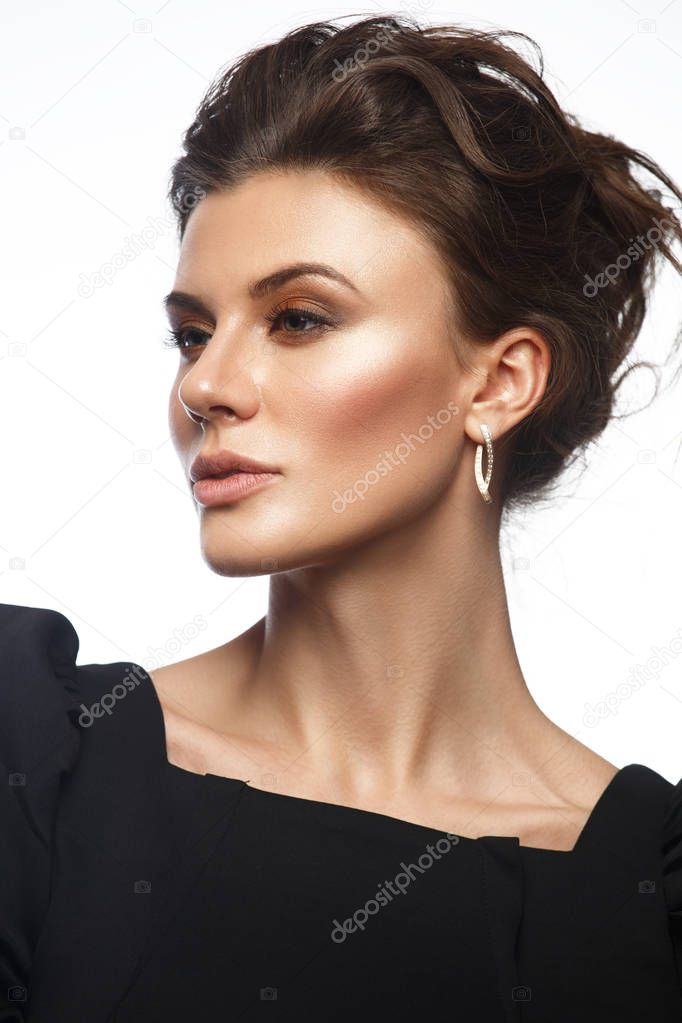 Portrait of a beautiful, self-sufficient and confident young woman with collected hair in the elegant black dress with makeup, white isolated background, studio photo