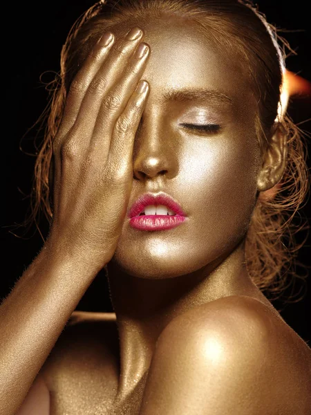 Glamoureuze portret van een mooie jonge vrouw met kunst van de creatieve lichaam gloeiende make-up. Gezicht is beschilderd met gouden kleur. Gouden glans van naakte huid. Studio zwarte achtergrond. — Stockfoto