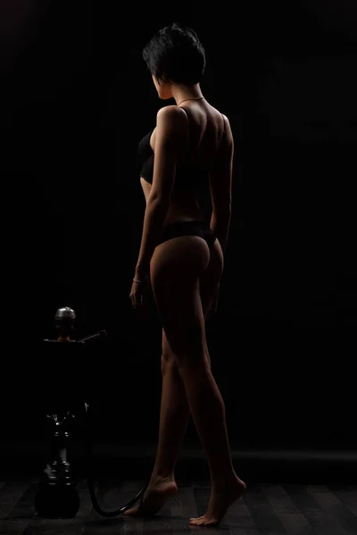 Сексуальная, красивая и привлекательная женщина с шикарным стройным телом в вялом нижнем белье позирует в темной студии. Привлекательная модель с соблазнительной фигурой и длинными ногами в черном нижнем белье — стоковое фото