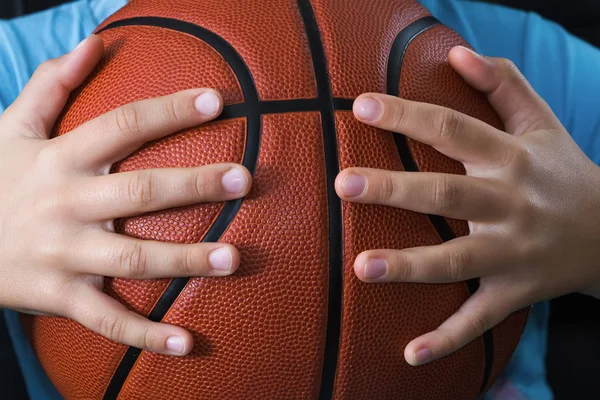 Basketball ball in the hands of a child.