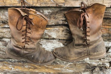 Ahşap bir duvarda asılı iki eski çizmeler