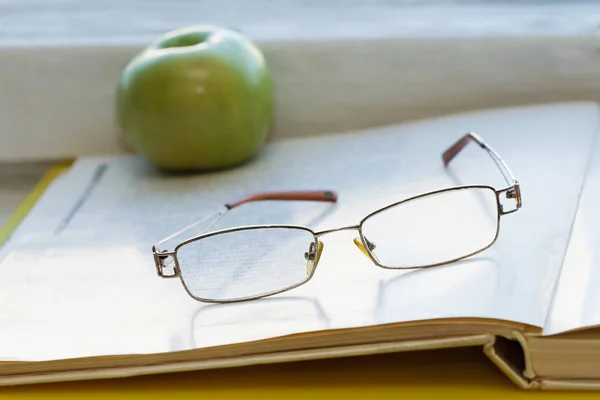 Livro aberto com óculos e maçã . — Fotografia de Stock