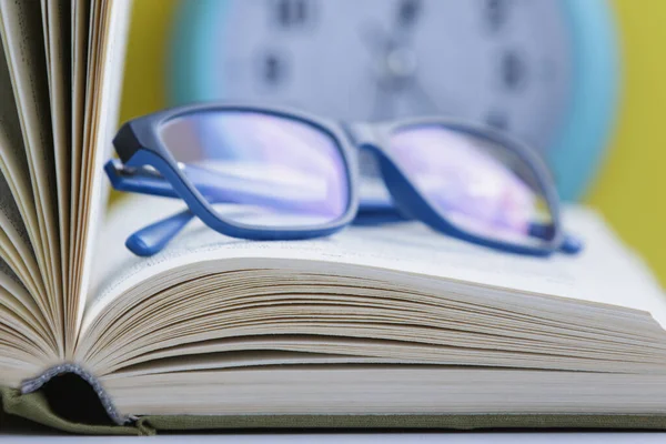 Livro aberto com óculos e um velho despertador . — Fotografia de Stock