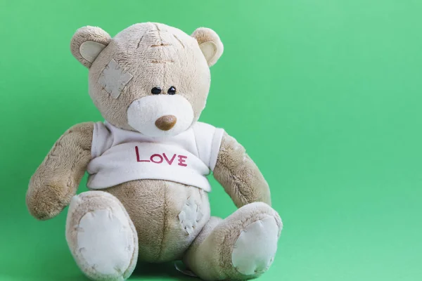 Zittende teddybeer op een groene achtergrond. — Stockfoto