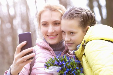 Annesiyle birlikte doğada selfie çeken bir kız.