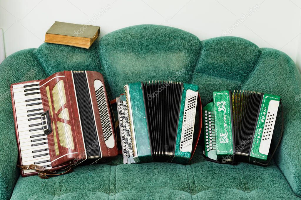 Old accordions with a book lie on a retro sofa