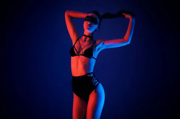 밝은 네온 색깔의 스포트 라이트와 함께 매혹적인 검은 란제리 모델 — 스톡 사진