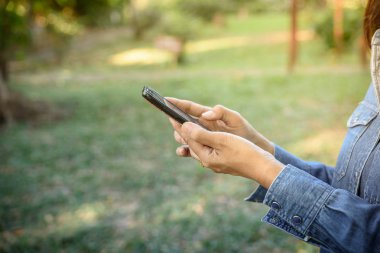 Kadın parkta bir akıllı telefon tutar.