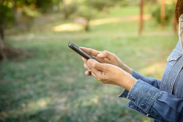 Kadın parkta bir akıllı telefon tutar.