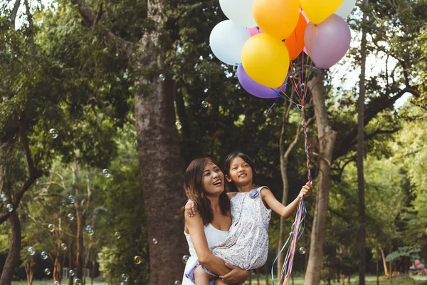 Mutlu anne ve kızı parkta renkli balon