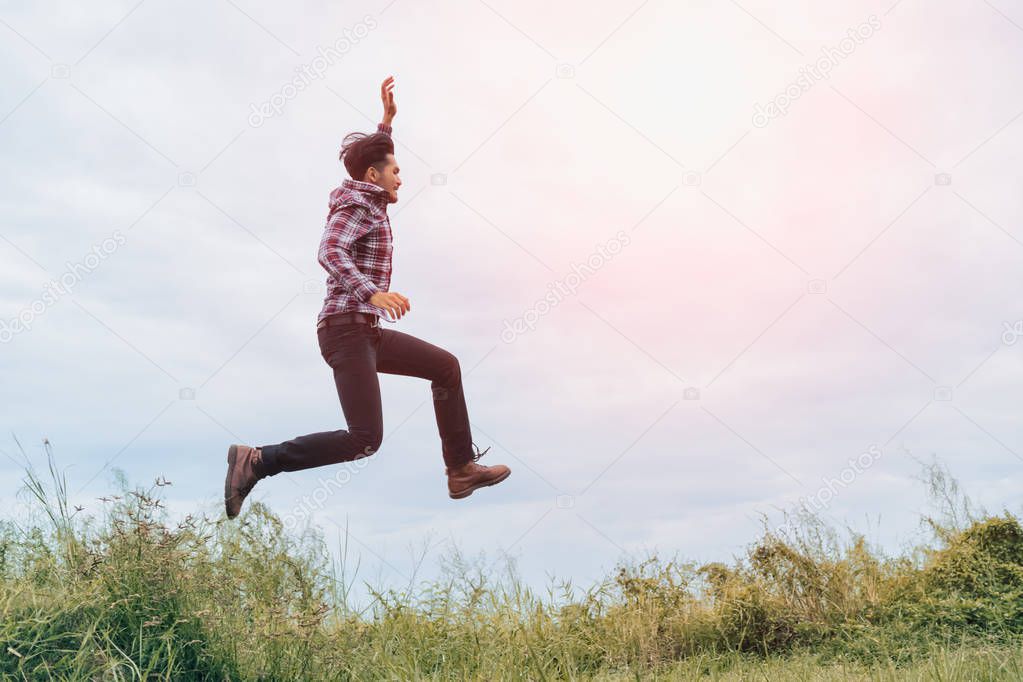  A man running and jumping with arms raised with energy for vict
