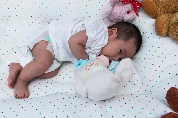 Noworodka leżąc na łóżku i picia mleka z butelki, butelki ostrości — Zdjęcie stockowe