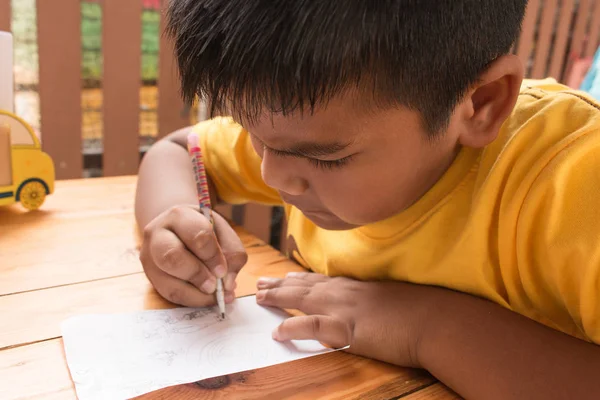 Мила дитина азіатський маленький хлопчик робить домашнє завдання на столі — стокове фото
