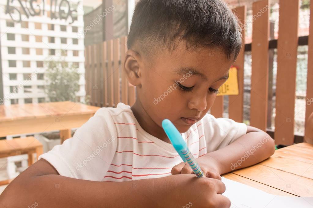 Cute child asian little boy doing homework on table 