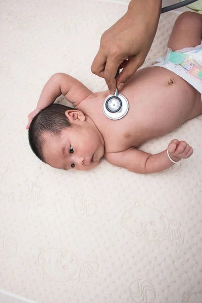 Médico de la mano examina bebé con estetoscopio, pediatra examina t —  Fotos de Stock