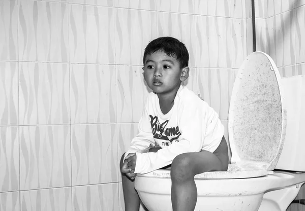 Cute child little asian boy defecate in toilet black and white t — Stock Image Cute child little asian boy defecate in toilet black and white t Stock Photo