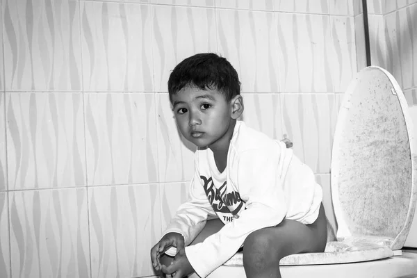Cute child little asian boy defecate in toilet black and white t — Stock Image Cute child little asian boy defecate in toilet black and white t Stock Picture