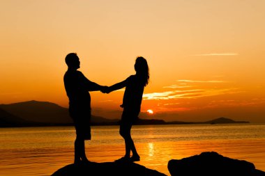 Romantik Çift aşk, gün batımı seyir taş üzerinde duran 