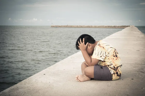 Mały chłopiec niezadowolony siedzi sam na most, dźwięk w vintage — Zdjęcie stockowe