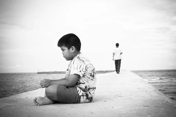 Mały chłopiec niezadowolony siedzi sama na most, czarno-biały ton — Zdjęcie stockowe