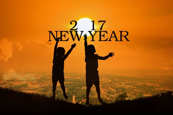 Concetto Anno nuovo 2017, silhouette del bambino saltare a toccare il testo di Capodanno — Foto Stock