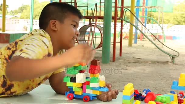 Pouco bonito asiático menino jogando com plástico blocos de construção no parque — Vídeo de Stock