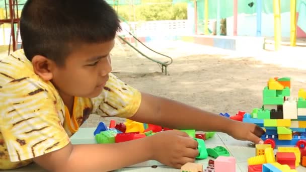 Pouco bonito asiático menino jogando com plástico blocos de construção no parque — Vídeo de Stock